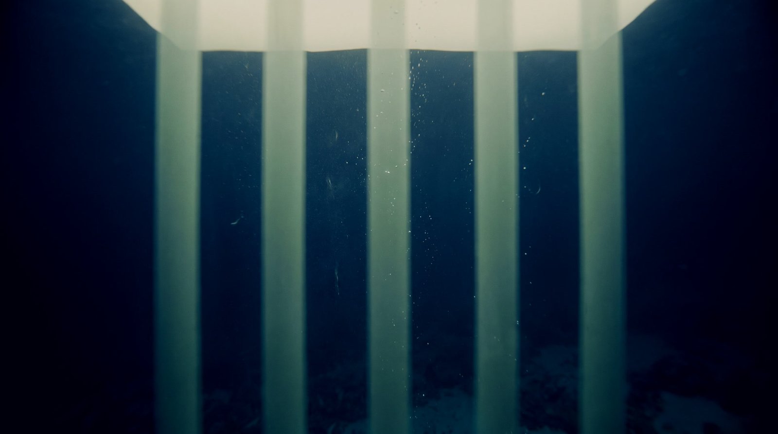 Layered planes of navy water receding into sage lit depth